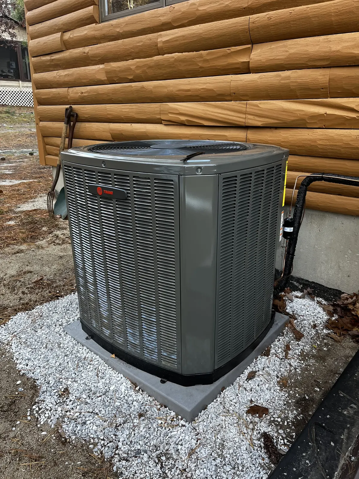 Heat pump condenser at a log cabin by TJM Climate Control, Southern NH & northern MA